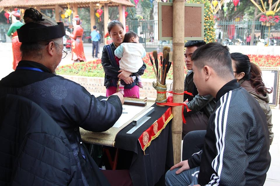 nguoi dan do ve van mieu xin chu ngay cuoi nam ong do dung may say toc de kip kho chu