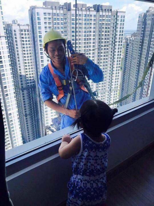hinh anh nguoi cong nhan cheo leo tren toa cao oc no nu cuoi hien voi be gai qua mat kinh gay xuc dong manh